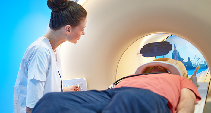 Eine Frau sieht einen Mann an, der in einem CT-Scanner liegt