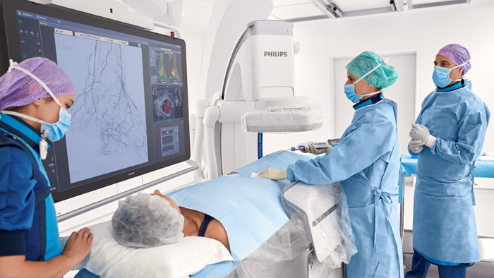 eine Frau in einem blauen Kittel und einer Maske, die an einem Patienten arbeitet