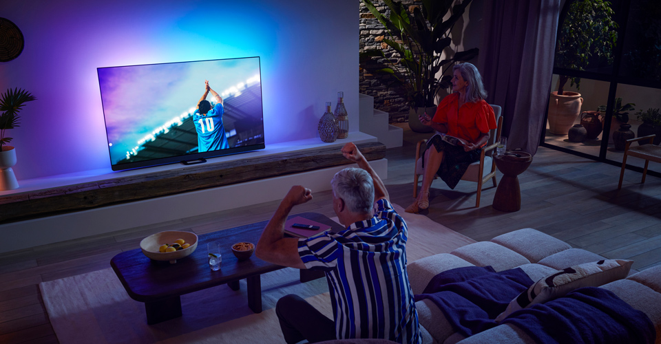 Eine Familie schaut eine Sport&uuml;bertragung auf einem OLED-TV