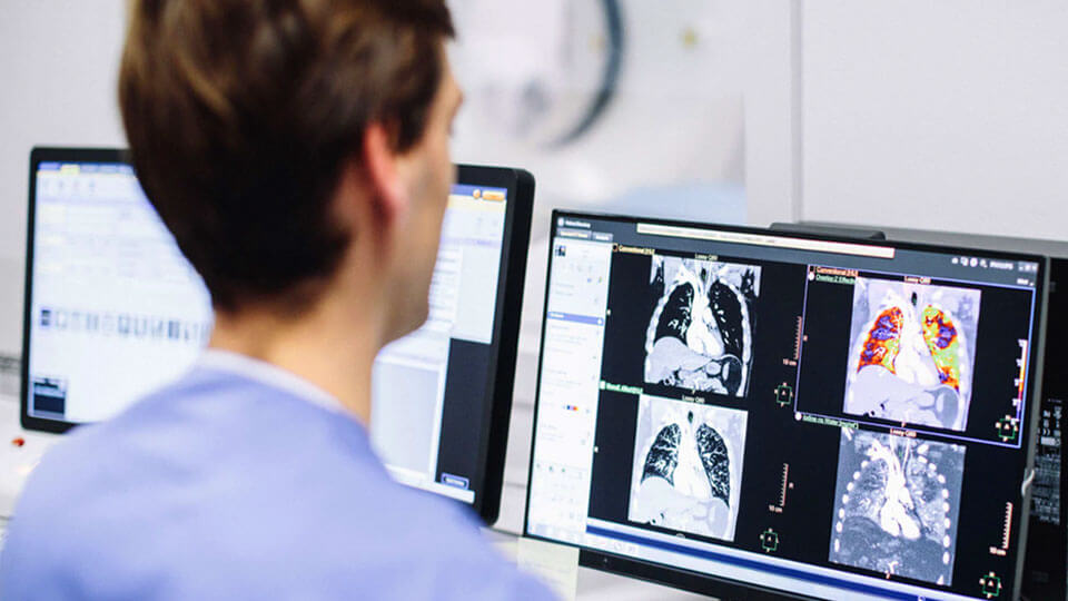 Foto eines MTRA, der klinische CT-Bilder auf einem Monitor &uuml;berpr&uuml;ft