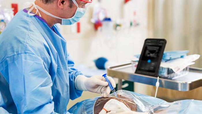 Medizinische Fachkraft beim Einsatz des Handheld-Ultraschallger&auml;ts und Beobachten der Ergebnisse